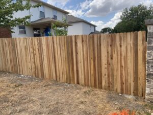 A newly installed wood picket fence next to a stone pillar by Good Neighbor Fencing and Construction in Austin, TX.