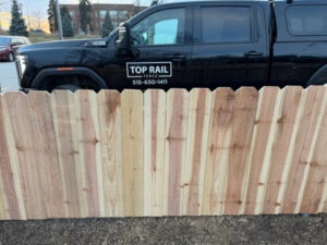A newly installed wood picket fence with a Top Rail Fence branded truck, showcasing work in West Des Moines, IA.
