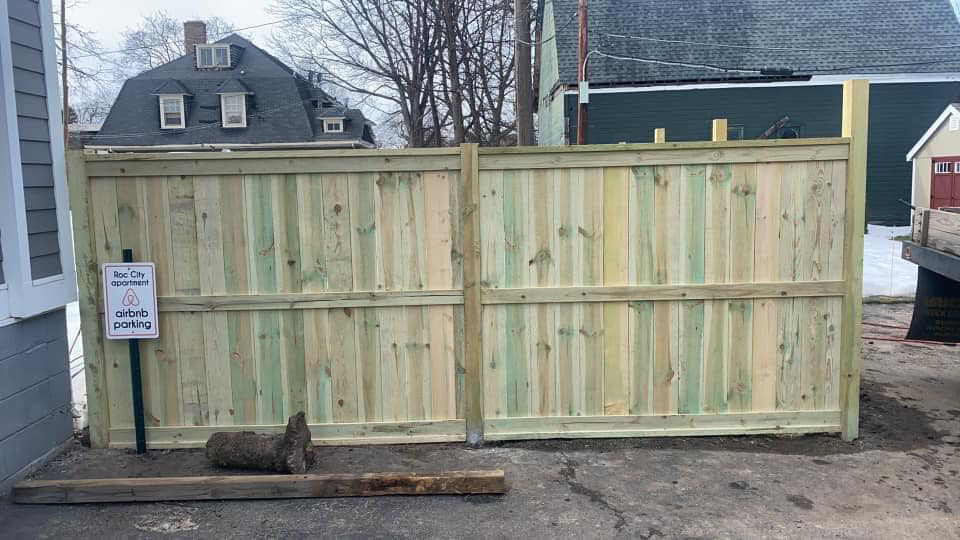 A newly installed wood privacy fence next to an Airbnb parking area by STILL Fencing in Rochester, NY.
