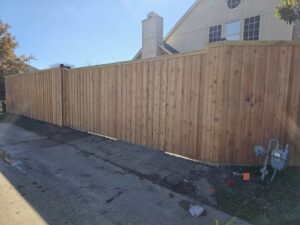 A newly installed wood privacy fence along a residential driveway by Straight Shot Solutions, LLC in Fort Worth, TX.