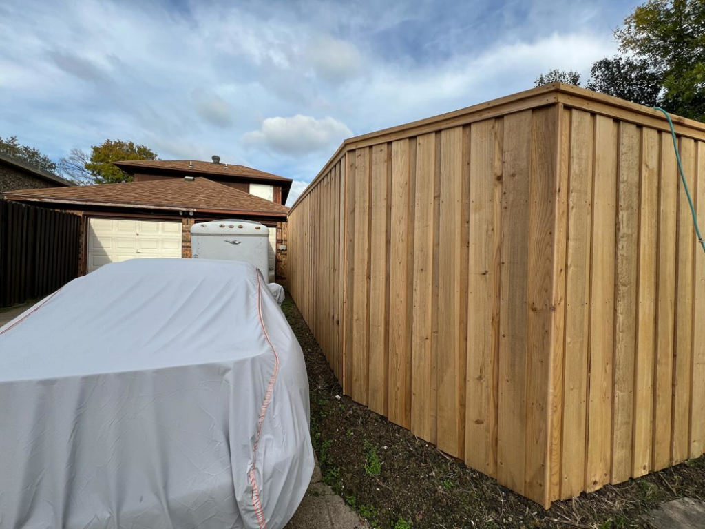 A newly installed wooden privacy fence along a property line next to a driveway by True Ways Services LLC in Mesquite, TX.