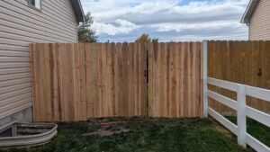 A newly installed wood privacy fence with a gate next to a house by 208 Fence and Gate in Idaho Falls, ID.
