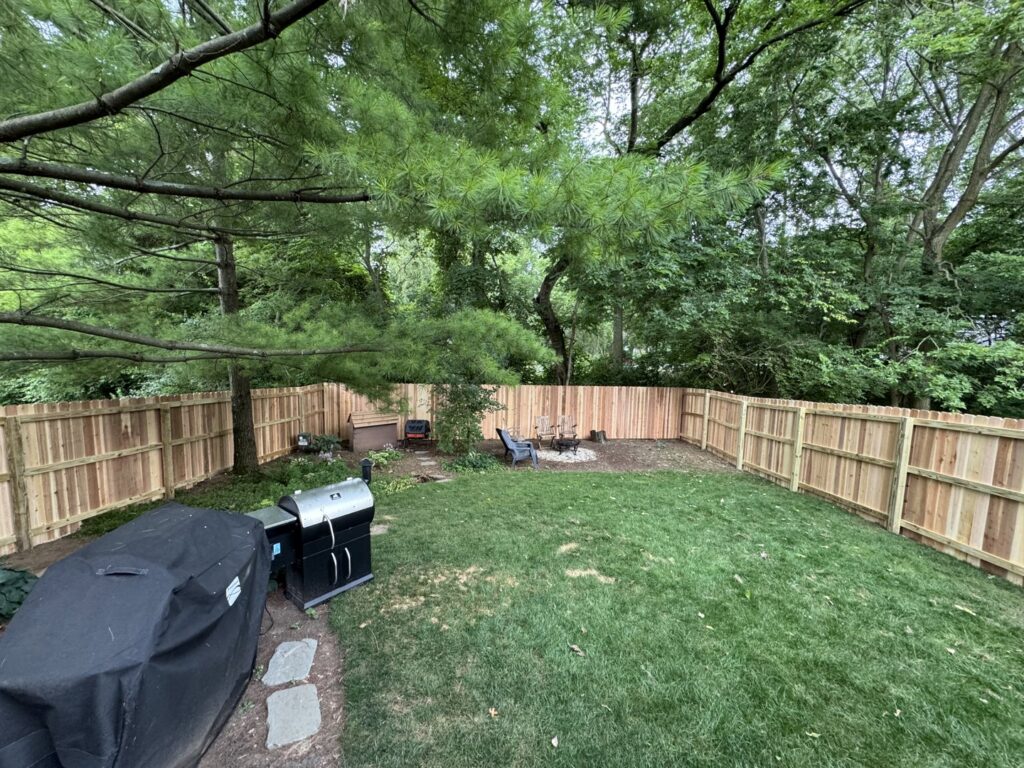 A newly installed wood privacy fence surrounding a backyard with a grill by Central Ohio Fence in Newark, OH.