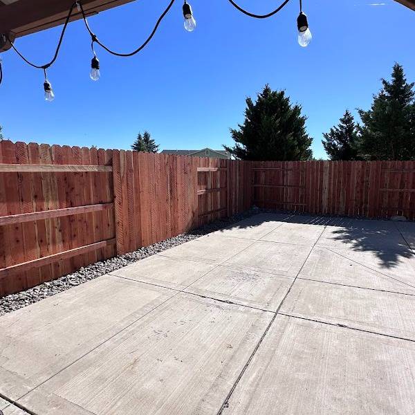 A newly installed wooden privacy fence enclosing a backyard with a concrete patio by Mule Fence Inc. in Sparks, NV.