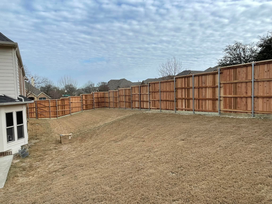A newly installed wood privacy fence in a residential backyard by Plano Fence and Arbor Pro in Plano, TX.
