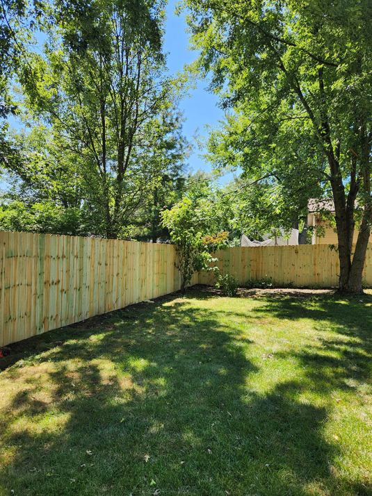 A newly installed wooden privacy fence bordering a backyard, built by Tussing's Fence in Ann Arbor, MI.