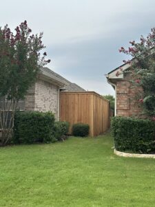 A newly installed natural wood privacy fence situated between two residential homes, built by NTX-Exterior Services in Dallas, TX.