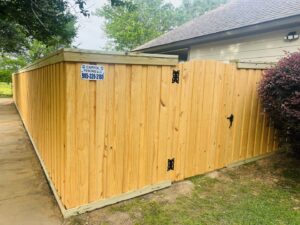 A newly installed wooden privacy fence featuring a curved top gate next to a residential home by Capitol Fencing in Baton Rouge, LA.