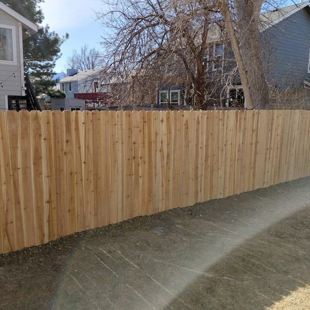 A newly installed wood privacy fence with dog-eared pickets in a residential backyard by Done Wright Fencing and Welding in Denver, CO.