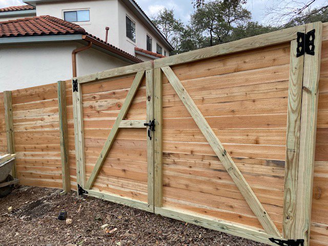 A newly installed wood privacy fence with a double gate for a residential property by National Fence Services, LLC in Macon, GA.