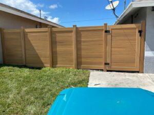 A newly installed wood privacy fence with a gate in a residential backyard by Palm's Fence of Miami, FL.