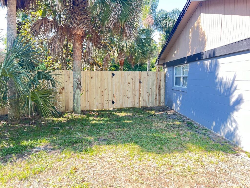 A newly installed wood privacy fence with a gate in a residential backyard by Boost My Home in St. Augustine, FL.