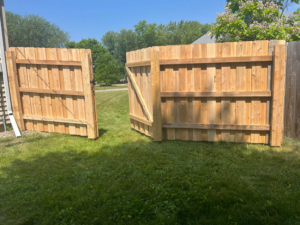 A newly installed wood privacy fence with a gate in a residential backyard by Northern Fence, Inc. in Appleton, WI.