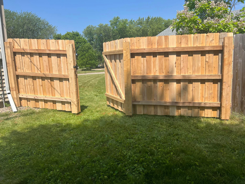 A newly installed wood privacy fence with a gate in a residential backyard by Northern Fence, Inc. in Appleton, WI.