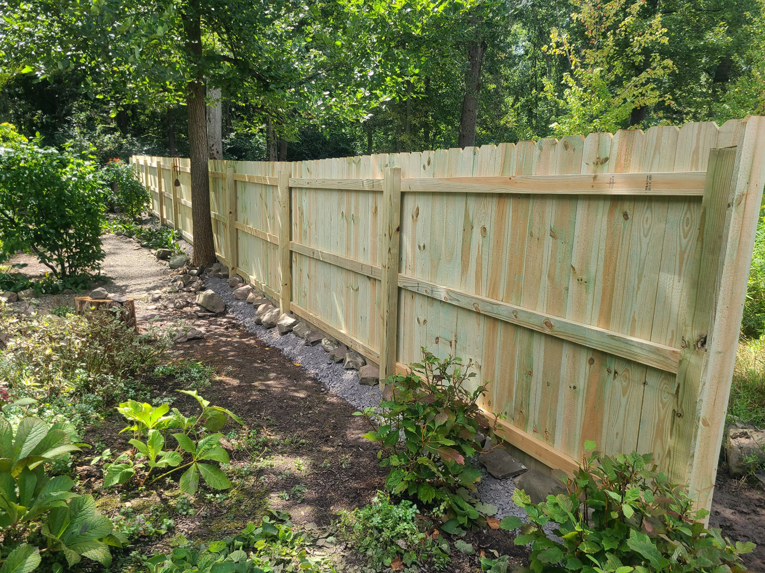 A newly installed wood privacy fence in a residential backyard by Camp Carlson Fencing in Rochester, NY.