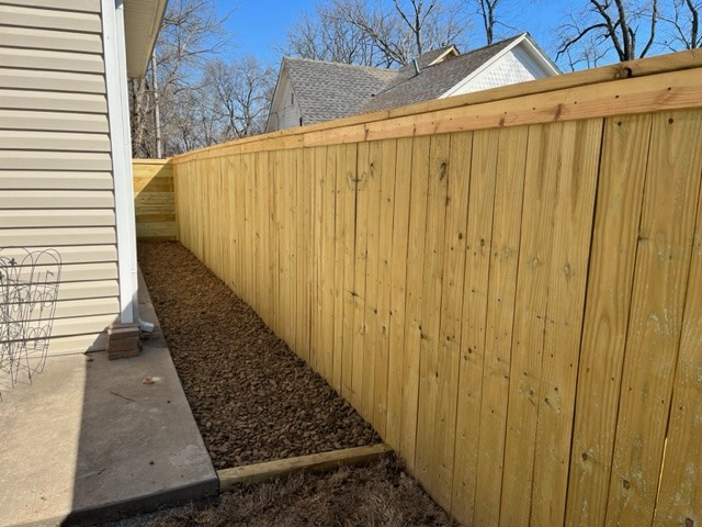 A newly installed wood privacy fence next to a house by Fence Solutions of NWA in Gravette, AR.