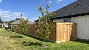 A newly installed wood privacy fence with a gate next to a residential home by GOAT Fence Company in Houston, TX.