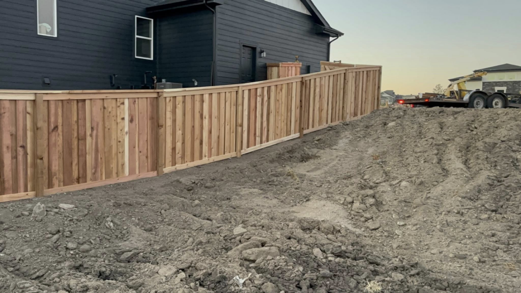 Newly installed wood privacy fence on a sloped property by HG Fencing LLC in Fountain, CO.
