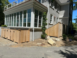 Newly installed wood privacy fence and gate structure next to a modern home by New England landscaping and fence inc in Lynn, MA.