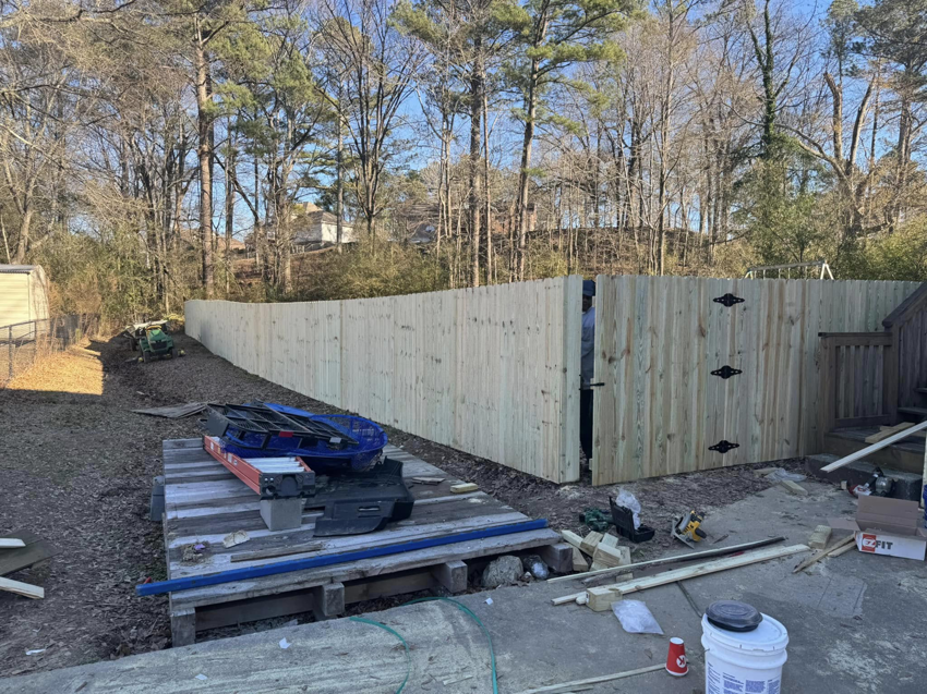 A new wood privacy fence with a gate recently installed by Precision Contracting LLC in Jupiter, FL, in a backyard.