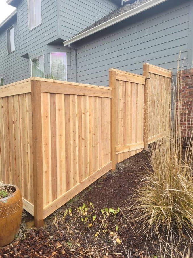 A newly installed wood privacy fence section built on a sloped terrain by Howell Fence Inc. in Oregon City, OR.