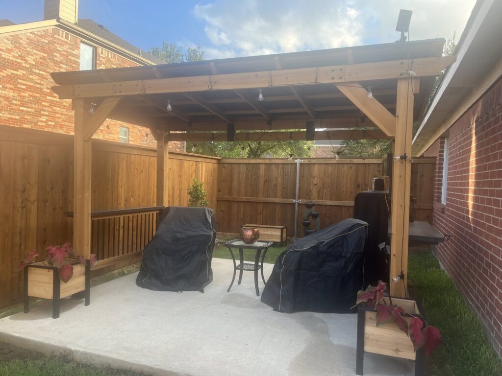 A new wood privacy fence providing a backdrop to a patio with a wooden pergola by EverFence in Dallas, TX.
