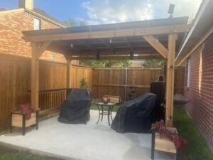 A new wood privacy fence providing a backdrop to a patio with a wooden pergola by EverFence in Dallas, TX.