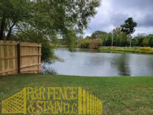 A newly installed wood privacy fence next to a pond by R&R Fence & Stain LLC in Madison, AL.
