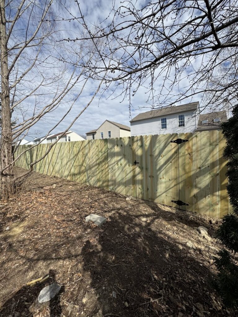 A newly installed wood privacy fence on a sloped residential backyard by Central Ohio Fence in Newark, OH.