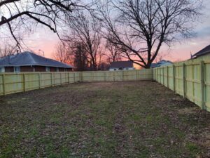 A newly installed wood privacy fence in a backyard at sunset by ACE and Sons Fence Company in Evansville, IN.