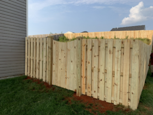 A newly installed natural wood privacy fence with a gate next to a home by Brock Brothers Fence in Mobile, AL.