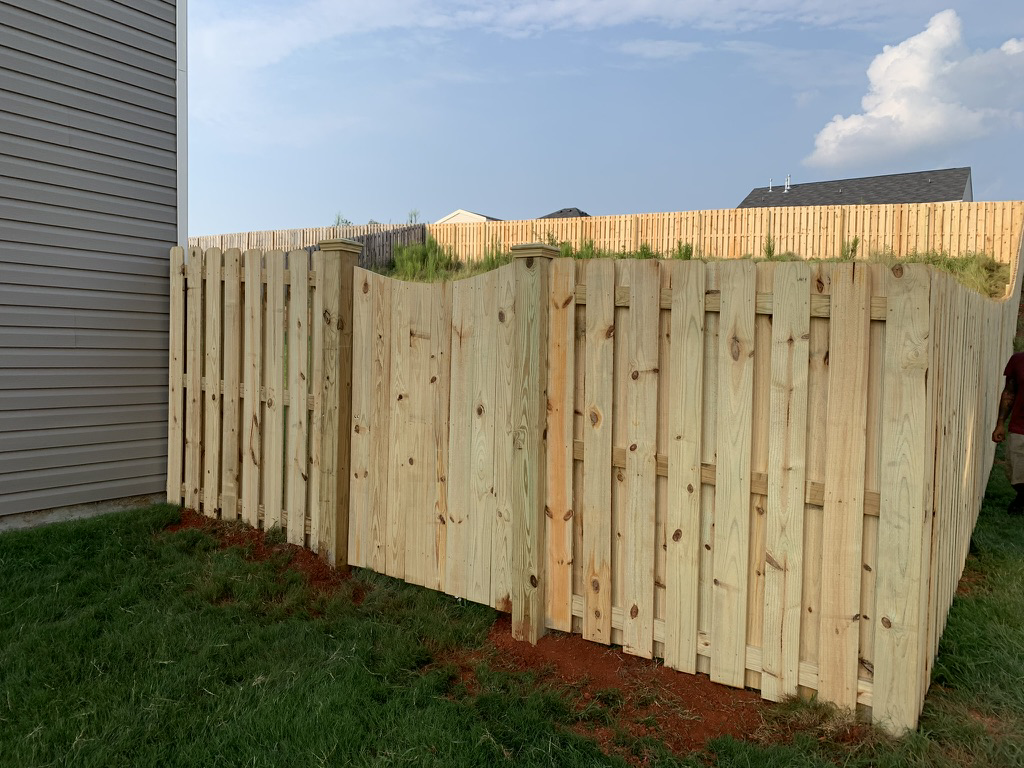 A newly installed natural wood privacy fence with a gate next to a home by Brock Brothers Fence in Mobile, AL.