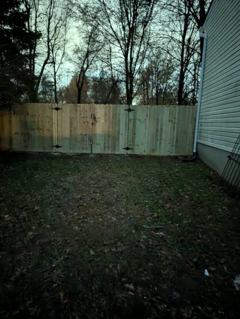 A newly installed wood privacy fence with a gate in a backyard by KY Fencing Unlimited in Louisville, KY.