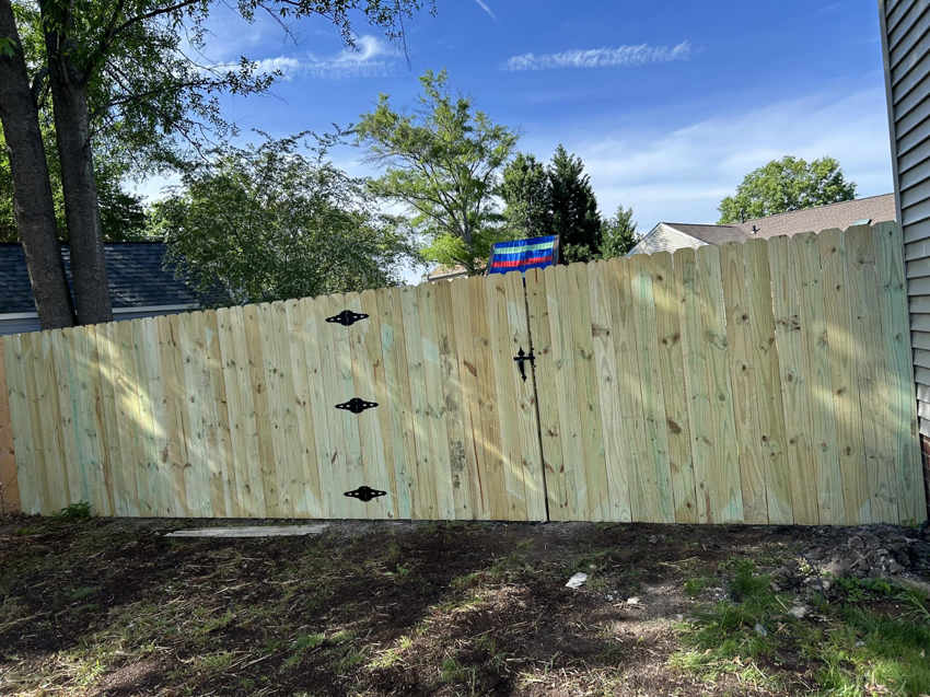 A new wood privacy fence with a gate installed in a residential backyard by Progressive Fences LLC in Dunn, NC.