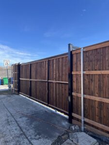 A newly installed wooden privacy fence featuring sturdy metal posts and a gate, completed by Reliable Texas Fencing in Fort Worth, TX.