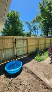 A newly installed wood privacy fence with a gate next to a residential home by Hotshot Fencing and Gates in Kansas City, MO.