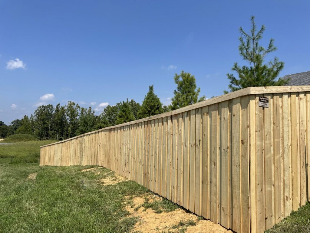A newly installed wood privacy fence with a business sign by Quality Deck & Fence LLC in Owensboro, KY