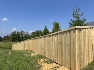 A newly installed wood privacy fence with a business sign by Quality Deck & Fence LLC in Owensboro, KY