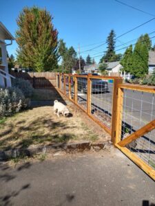 A newly installed wood and wire mesh fence line at a residential property by Howell Fence Inc. in Oregon City, OR.