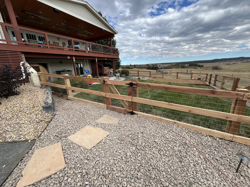 A newly installed wood and wire mesh fence with a gate by Denfence Team in Colorado Springs, CO