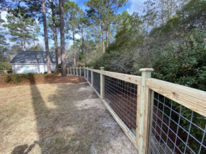 A long section of new wood and wire mesh perimeter fence installed by Renegade Fencing, LLC in Jacksonville, NC.