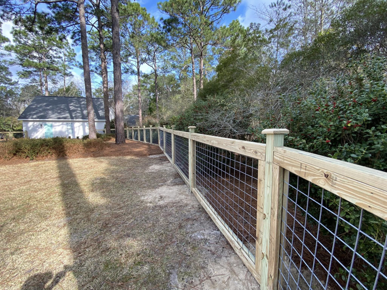 A long section of new wood and wire mesh perimeter fence installed by Renegade Fencing, LLC in Jacksonville, NC.