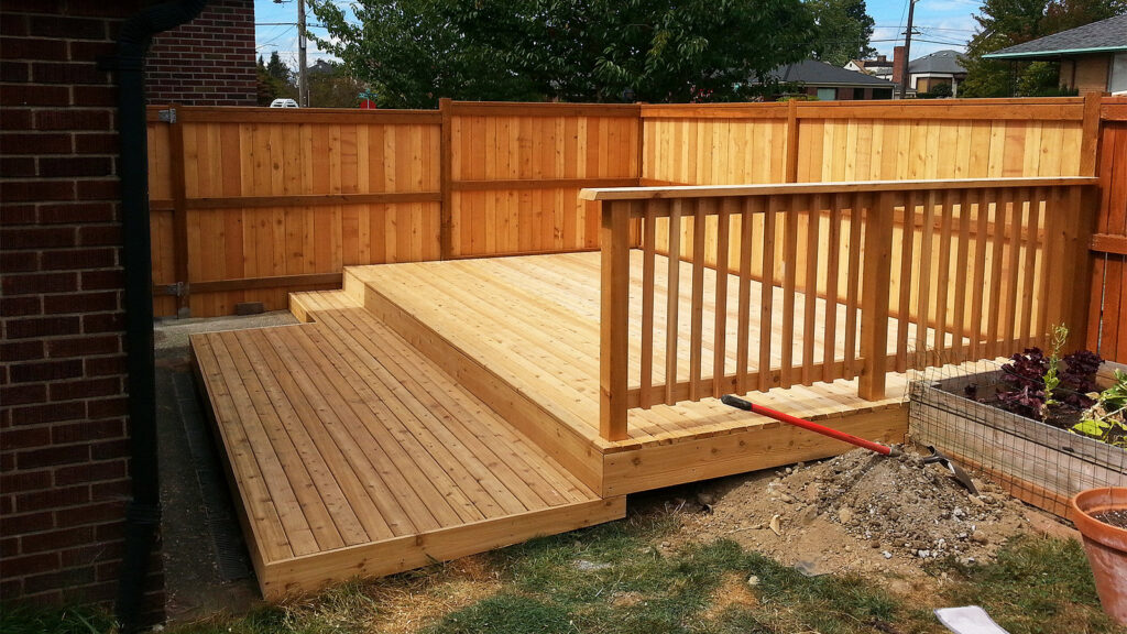 A newly constructed wooden deck with a matching privacy fence in the background by D-Fence of Tulsa in Tulsa, OK.