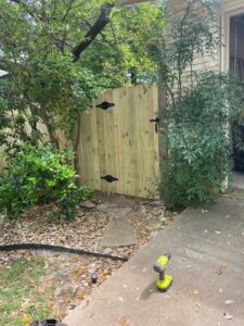 A newly installed wooden gate with black hardware, built by T&G Outdoor Services in Austin, TX.