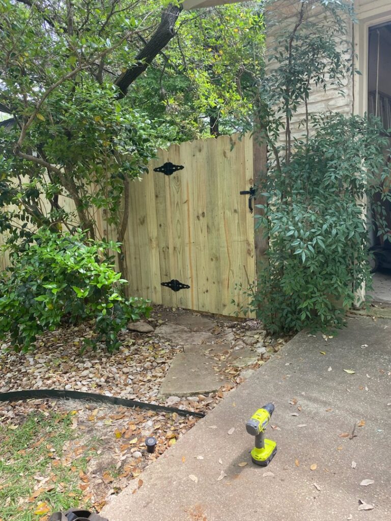 A newly installed wooden gate with black hardware, built by T&G Outdoor Services in Austin, TX.