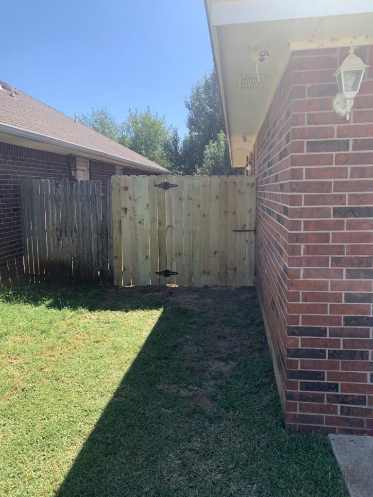A newly installed wooden privacy fence gate contrasting with an older fence by TOP TIER FENCE LLC in Oklahoma City, OK.