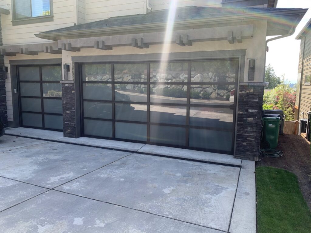 A newly installed wooden-look garage door on a house under construction by CHS Garage Repair of Seattle, WA.