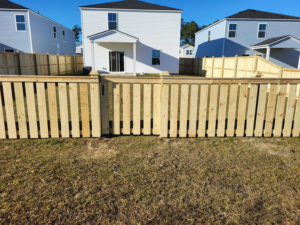 A newly installed wooden picket fence with a gate in a backyard by Lundquist Home Improvements, a fencing contractor in Mount Pleasant, SC.