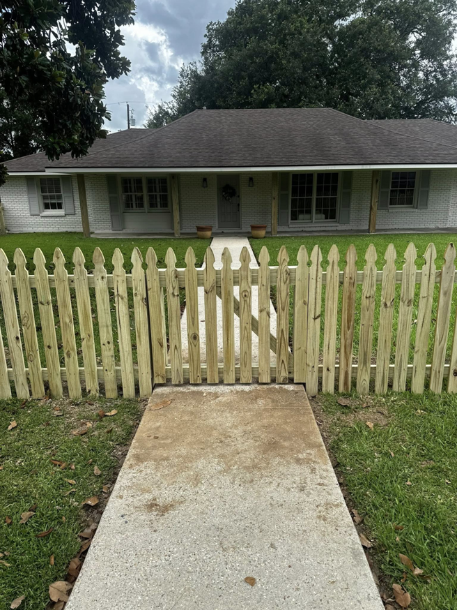A newly installed wooden picket fence with a gate in front of a house by J&L Fence in Zolfo Springs, FL.
