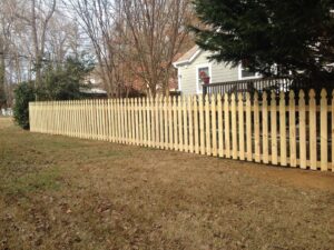 A newly installed wooden picket fence in a residential yard by Timber Fencing in Charlotte, NC.
